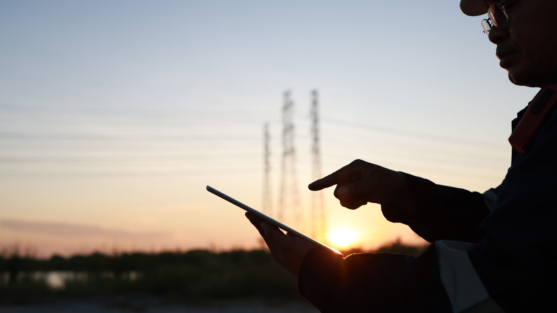 Silhouette Senior Electrical engineer using digital tablet at site line of project, Close up engineer hand using digital tablet on the job